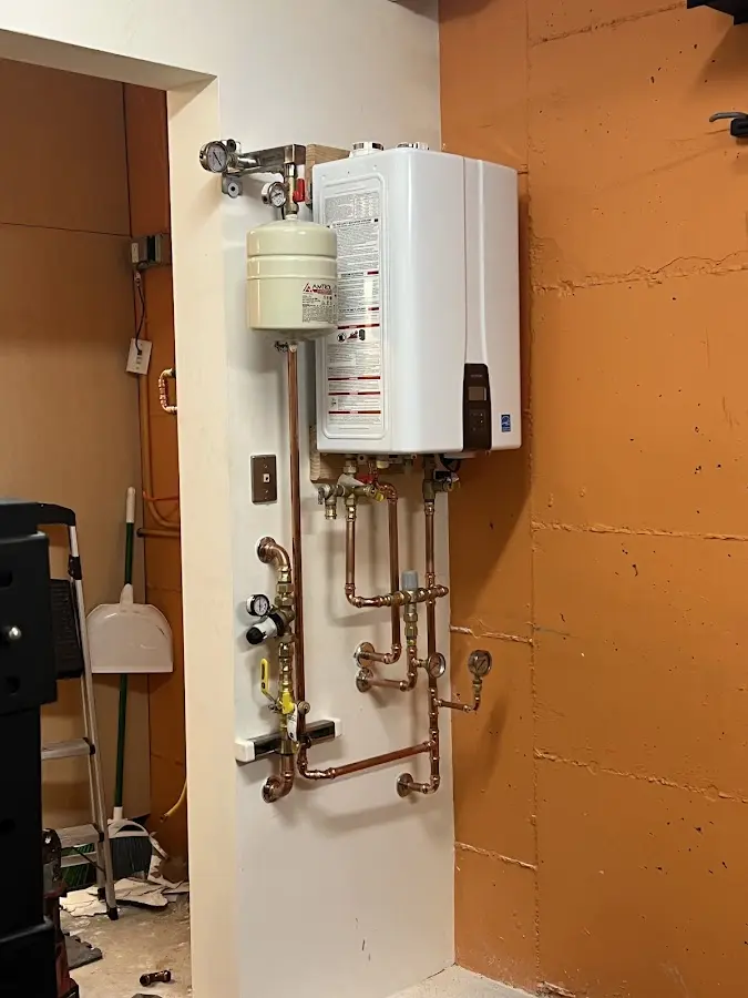 Plumbing technician inspecting water heater connections in Flushing